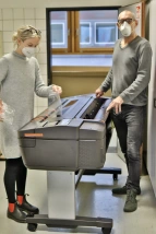 Der stellvertretende Schulleiter Carl Böhm und die Fachbereichsleitung Kunst Marta Huhnholt entfernen die Folie an dem frisch angelieferten Gerät